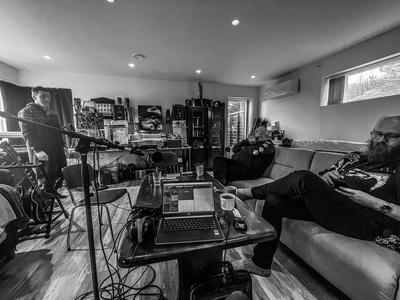 some people, microphones and a computer set up for making a podcast.